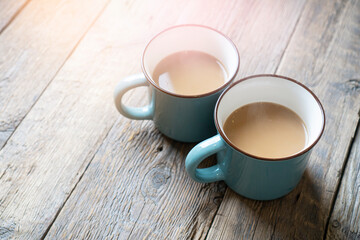 Two cups of coffee with milk stand on a rustic wooden table. Morning atmosphere.