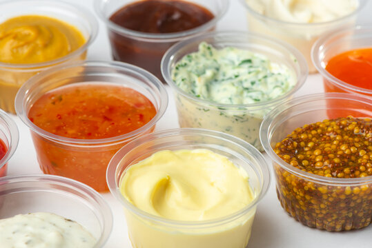 Variety of different sauces and condiments in small cups on white table
