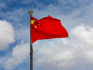 National flag of China or officially the People's Republic of China (PRC) strong waving in the wind on cloudy sky background. Blurred motion
