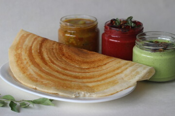 Crispy pancake made of rice and lentils. Served with spicy beetroot coconut condiments, coriander coconut condiments and sambar
