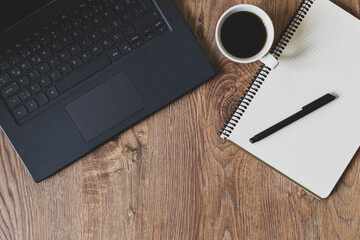 Computer, notebook-pen and coffee on wooden background