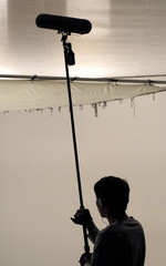 Boom Microphone hold up high by film crew. Boom man grabing a Big Boom microphone in studio while recording online movie. Film Production concept. © gnepphoto