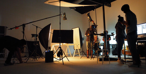Behind the shooting video production and film crew team. Silhouette of people in studio setting camera and lighting for shooting online video. Film production concept. - obrazy, fototapety, plakaty
