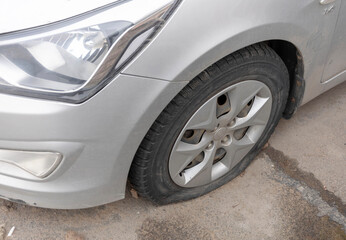 Flattened car tire after a car wheel puncture, requires repair