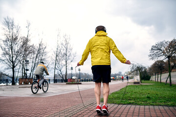 The athlete jumps on a racecar in the morning in a sports jacket and shorts. A cyclist passes. The...
