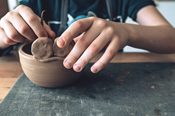 Hands of a young artist, modeling a clay bowl in art studio.  Traditional pottery craft. Ceramics workshop concept