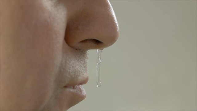 Close-up of an adult man's face with drooping snot from his nose