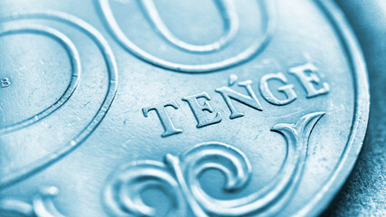 Translation: tenge. Fragment of a Kazakh coin in 50 tenge. Light blue tinted background or wallpaper. The name of the currency in Latin. Backdrop about economy, money and banking in Kazakhstan