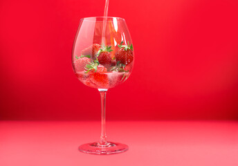 Bright juicy selected strawberries in a large glass with soda.