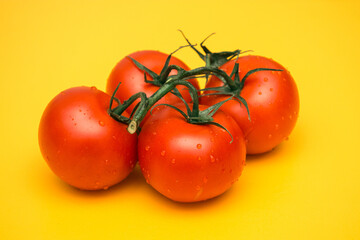 Red ripe tomatoes on a yellow background. Preparing a salad of vegetables. Natural products from the beds.