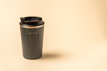 Reusable mug, plastic travel coffee mug to go. Plastic mug with silicone holder on natural shade beige background.