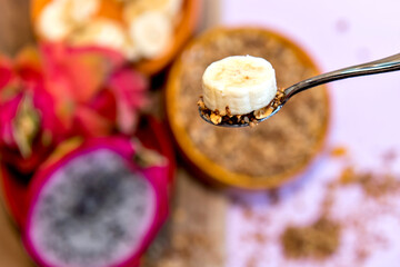 Plate with sliced ​​bananas, granola and pitaya cut in half. Top view.