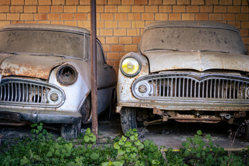 two Vintage cars left standing and falling apart in a shelter – image
