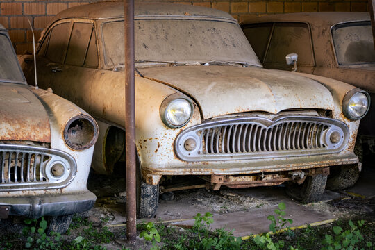 two Vintage cars left standing and falling apart in a shelter – image