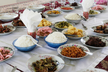 Fototapeta na wymiar Served food on floor dining style with bokeh background. Masakan Padang, Indonesian traditional cuisine and culture. Ramadan month and Islam Eid Al Fitr and Al Adha celebration. 