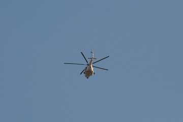Fototapeta na wymiar white helicopter flies away in the sky, rear view