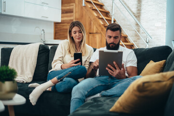 Couple using a digital tablet and a smartphone at home