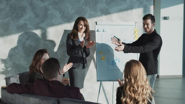 Diverse group of casual looking coworkers having small cozy conference, discussing current situation and upcoming projects. Colleagues having good reaction, clapping happily. Concept of teamwork.