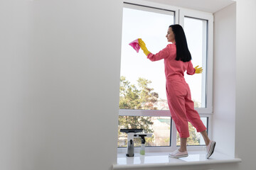 Fototapeta na wymiar Young caucasian woman cleaning windows. Housekeeping concept.