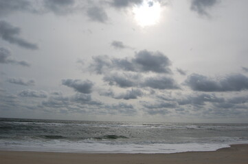 Fototapeta premium Rays of sunshine breaking through the clouds, casting light on the Atlantic Ocean, Assateague Island, Maryland.