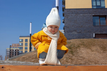 Beautiful baby in an orange coat and white hat and scarf