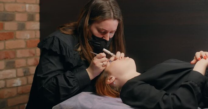 Lashmaker does the eyelash lamination procedure for the client in the beauty salon, cosmetic services, beauty care procedures, 4k 60p Prores HQ