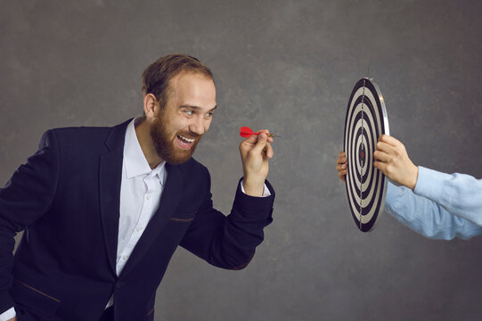 Ambitious Businessman Aiming Red Dart At Target Dartboard Determined To Throw It And Hit Bulls Eye, Side View. Setting Business Goal, Facing Challenge, Using Opportunities, Achieving Objective Concept