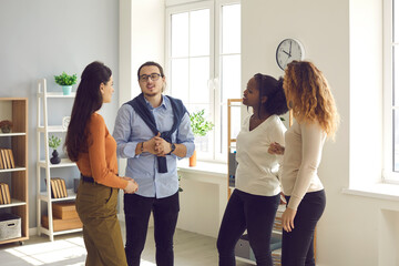 Intelligent young diverse business people or coworkers communicating, discussing work and exchanging opinions in informal office meeting. Group of interested women listening to smart male colleague