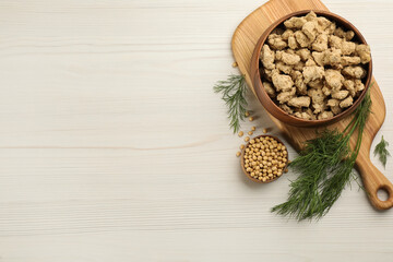 Dried soy meat in bowl on white wooden table, flat lay. Space for text