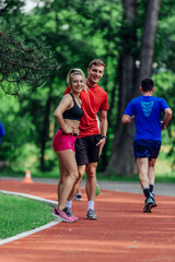 Obraz premium Young couple stretching before starting their morning jogging routine on a tartan track at the park.