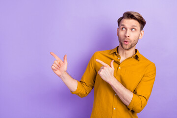 Photo of impressed man look interested indicate fingers empty space isolated on violet color...