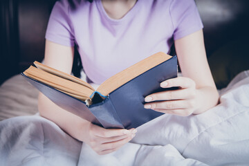 young girl reading a book in bed