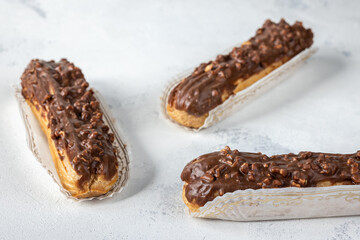 Three chocolate eclairs on white background, selective focus