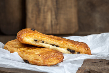 French pastries, tasty chocolate puff bakery on white paper and wooden brown background