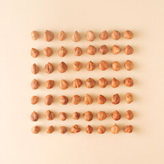 Raw hazelnuts arranged in a cube on a cream background. The concept of healthy food.