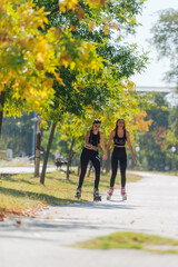 Obraz premium Full-length picture of sexy sportswomen rollerskating in the park