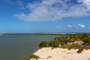 Fototapeta na wymiar Vegetation and sand dunes of the dry mangrove (Dunas do Mangue Seco) in Bahia providing a beautiful view of the blue sea.