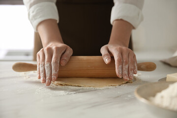 Obraz na płótnie Canvas Woman rolling dough at table in kitchen, closeup