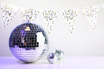 Fototapeta na wymiar Shiny disco balls on white wooden table. Space for text