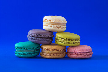 Obraz na płótnie Canvas Colorful macaroons in a pile isolated on a blue background.