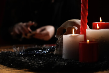 Soothsayer at table indoors, focus on skull and candles