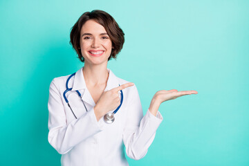 Photo of young woman doctor happy smile indicate finger product promo offer advert isolated over...