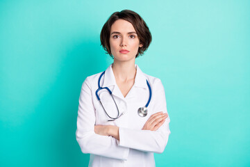 Photo of young woman serious confident crossed hands doctor surgeon clinic isolated over teal color background