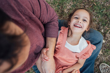 Dad tickling laughing daughter in his lap