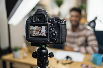 Afro american male blogger using professional camera for live video with subscribers while staying at home. Social media and technology concept.