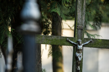 Stary, porośnięty mchem, drewniany krzyż z postacią Jezusa.