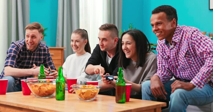 Playful diverse friends playing video games online and having fun at home