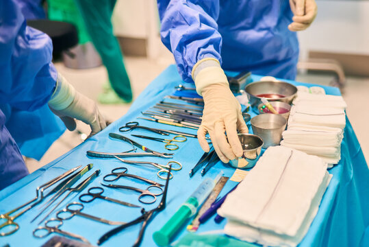sterile operating table in the operating room with a variety of surgical tools in a row. Surgeon's hand holds disinfectant liquid.