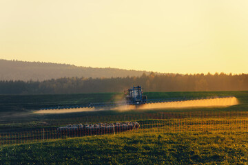 Fototapeta premium Farming spraying his pastures or crop in golden light