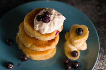 small thick pancake with berries and sour cream on a beautiful blue plate home cooking tomorrow with goodies